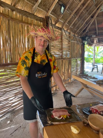 Allen showing off the fish he is making. He is wearing a fun hat and tropical shirt.