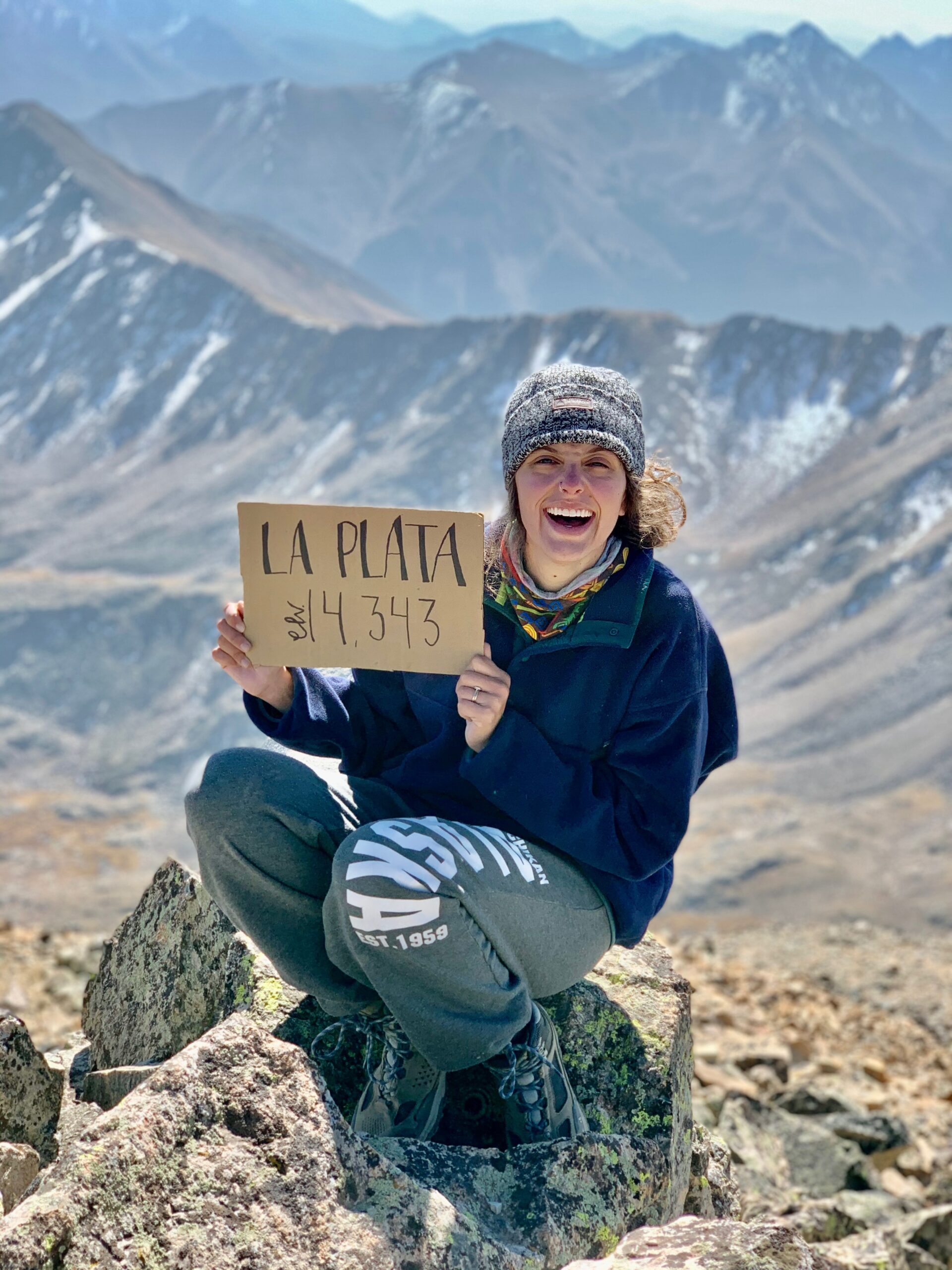 crysahna at the top of la plata peak holding a sign